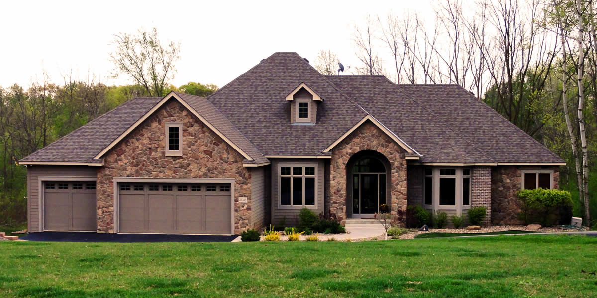 Home with siding, roofing, windows, soffit, facia, trim, and stone work