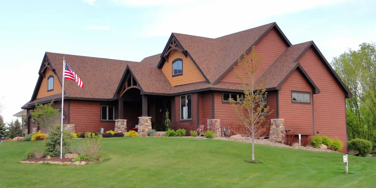 Home with siding, roofing, windows, soffit, facia, trim, and stone work